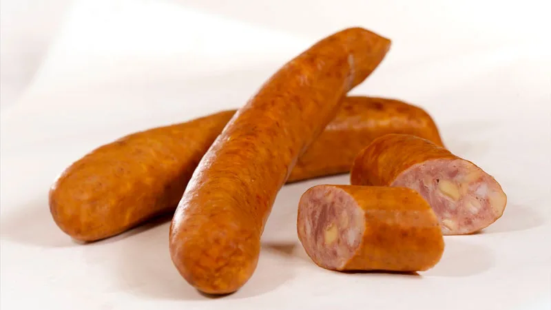 Eine aufgeschnittene Käsekrainer mit eingelegten Käsestücken